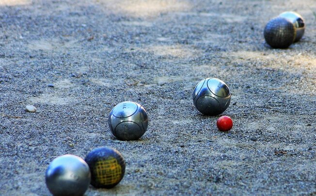 Persone anziane che giocano a bocce in un centro sportivo di paese