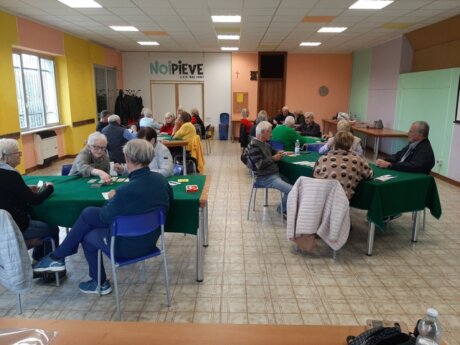 Persone sorridenti sedute ai tavoli mentre giocano a carte