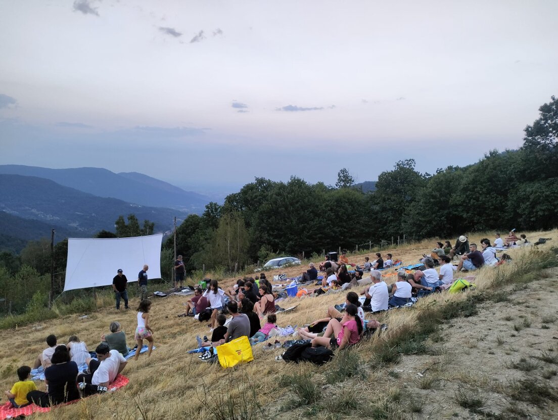 Palco illuminato con persone che recitano davanti a un pubblico